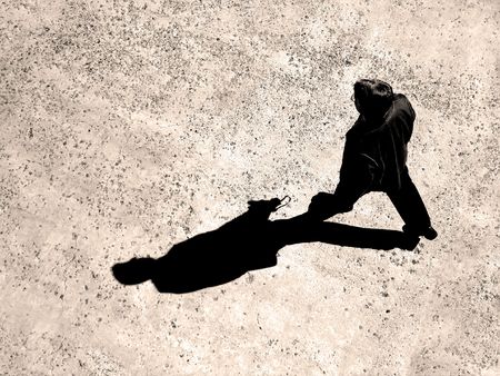 Man walking on sidewalk with black shadowの写真素材