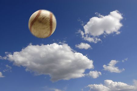 Baseball flying through the air with clouds and sky in backgroundの写真素材