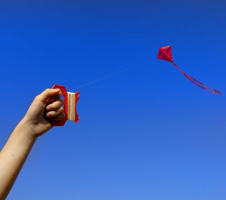 Girl flying a kite in a park with blue skyの写真素材