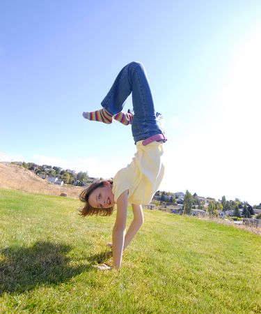 Young girl doing cartwheel across green grass