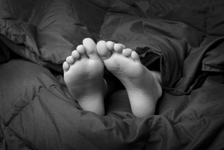 Little girl sleeping with feet poking out of blanketsの写真素材