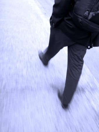 Businessman walking  on sidewalk and holding briefcasesの写真素材