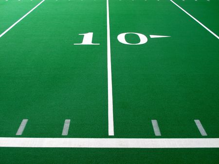 Football field with green turf and white yardlines and markers                       