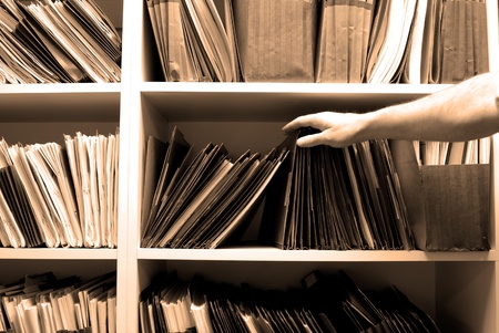 Man reaching for files on shelf in a file roomの写真素材