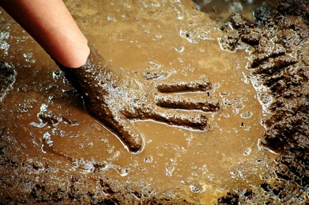 Hand of child playing in muddy dirt and waterの写真素材