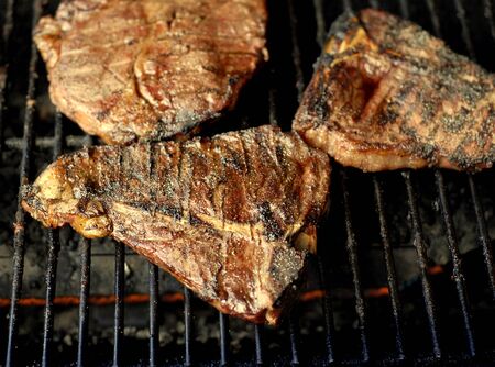 Several steaks on grill cooking under a flameの写真素材