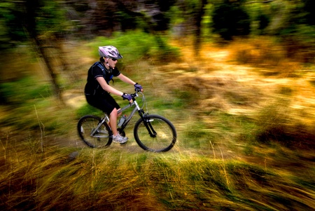 Young Woman Riding Mountain Bike in Wildernessの写真素材