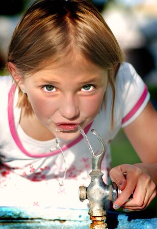Young Girl drinking water from water fountainの写真素材