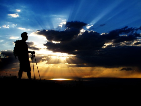 Man hiking up a mountain at sunset or sunriseの写真素材