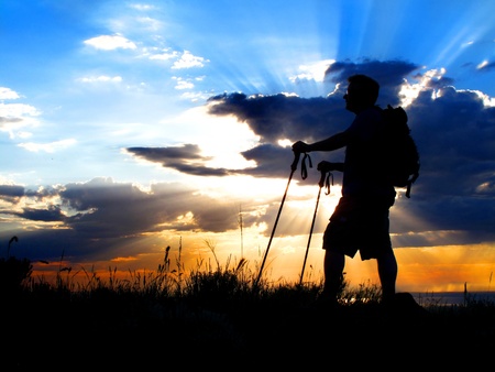 Man hiking up a mountain at sunset or sunriseの写真素材