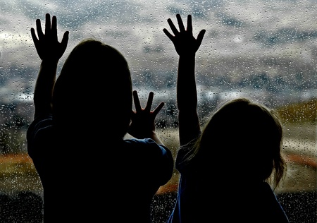 Little girl looking out window on a rainy dayの写真素材
