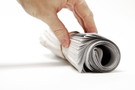 Rolled up newspaper isolated on white background with hand reachingの写真素材