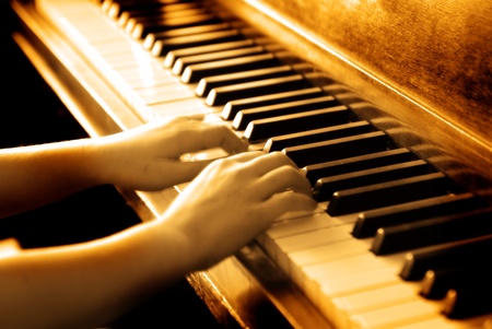 Small hands playing piano keys with wood grain and sepia toneの写真素材