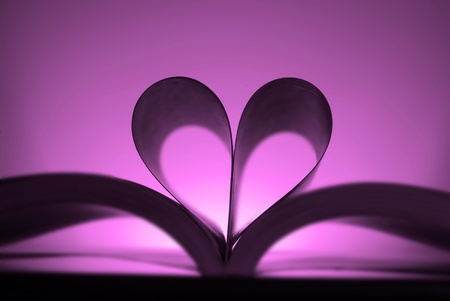 A large single book sitting with pages open in teh shape of a heartの写真素材