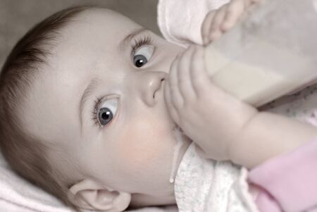 Baby drinking from bottke with nipple in mouthの写真素材