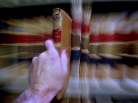 Close up of hand pulling out a book on shelfの写真素材