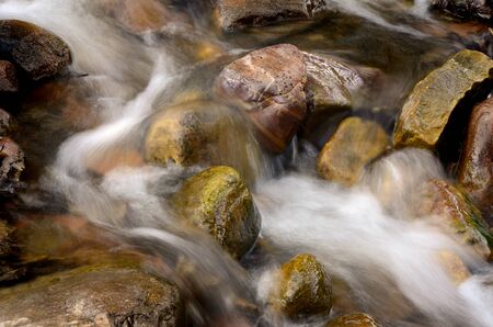 Creek or stream water flowing past rocks and stones