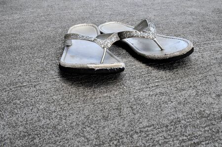 Pair of old worn sandals or flip flops on cementの写真素材