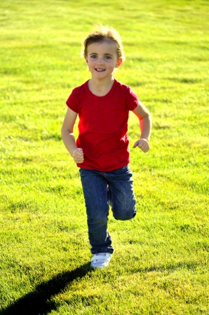Young girl running on grass during bright summer dayの写真素材