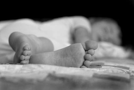 Portrait of little girl sleeping with focus on feetの写真素材
