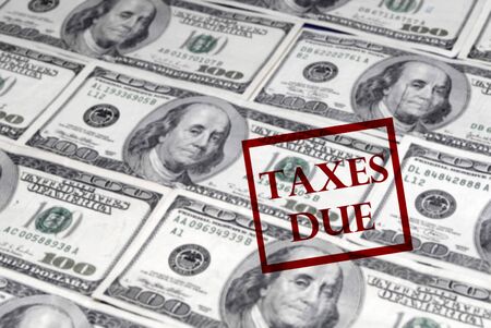 Several one hundred dollar bills in a row creating a background with Taxes Due stampの写真素材
