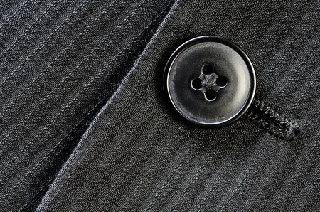 Detail of closeup of suit button on pin stripped cloth