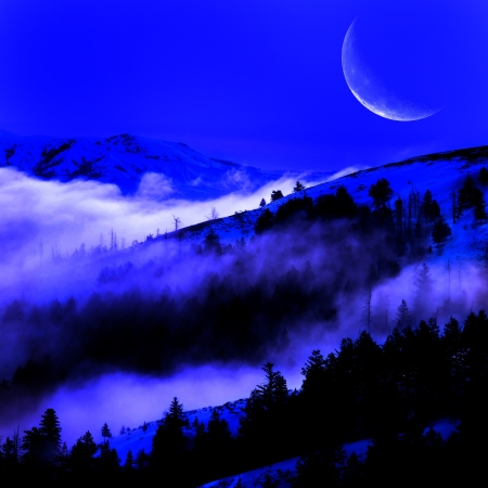 Valley with fog and mountains in background on a night with cresent moonの写真素材