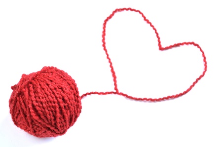Red yarn or string heart away from rolled ballの写真素材