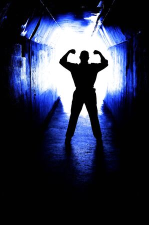 Man at the end of a tunnel with arms raised in victory over fear and becaus eof accomplishmentの写真素材