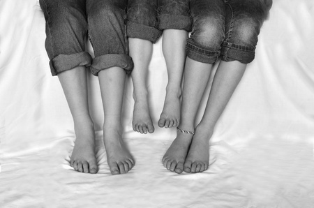 Family sitting with jeans rolled up sharing fun moment of happiness together bare feetの写真素材
