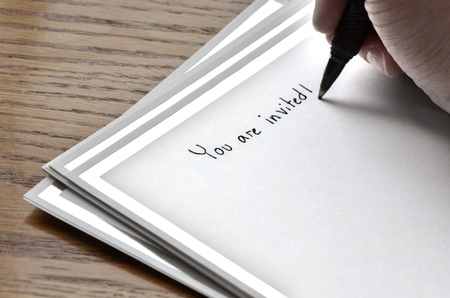 Person writing invitation on card with pen and inkの写真素材