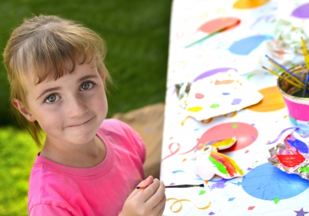 Young girl artist painting with paints and brushes at art tableの写真素材