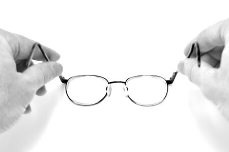 Person holding black eyeglasses on white looking through lensesの写真素材