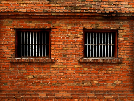 Detail shot of an old brick wall with barred windows for securityの写真素材