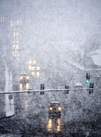 Snowy winter road with cars driving on roadway in snow stormの写真素材