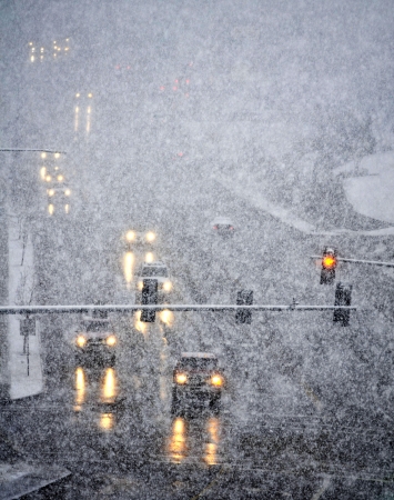Snowy winter road with cars driving on roadway in snow stormの写真素材