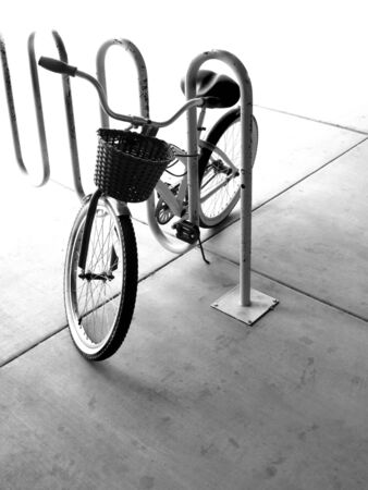 A single bike with basket in a bike rack in a cityの写真素材