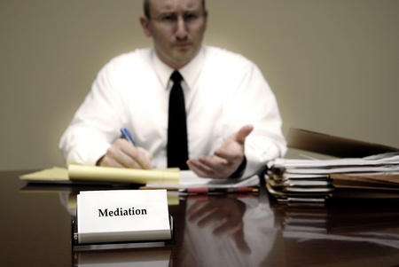Attorney at Law sitting at desk holding pen with files with a card for Mediationの写真素材