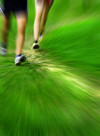 Zooming detail on runners running a race on grassy courseの写真素材
