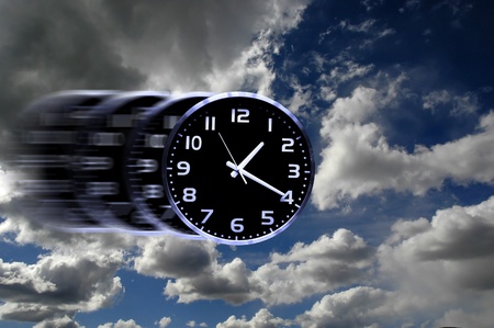 Detail of blurred speedy clock face with numbers and hands showing time in skyの写真素材
