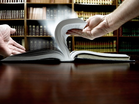 Hands holding an old book with library in backgroundの写真素材