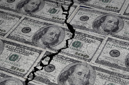 Several American Dollars ripped or torn in half symbolizing the destruction of the economy