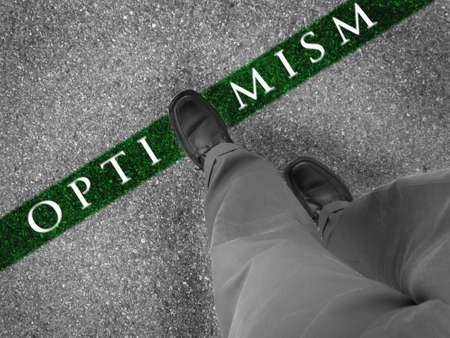 Man walking across a green line with words optimismの写真素材