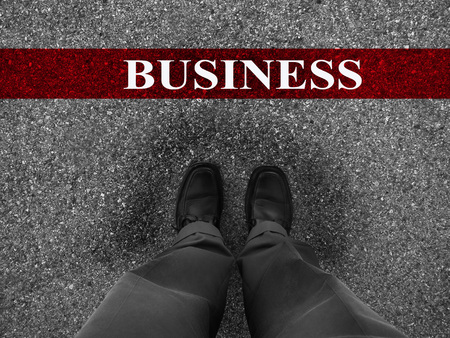 Businessman standing on asphalt starting line with motivation word of Businessの写真素材