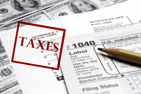 Current tax forms and pencil on money with stamp for taxesの写真素材