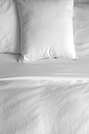 Group of several white pillows on a bed with headboardの写真素材