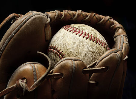 Worn old baseball in brown leather mitt or gloveの写真素材