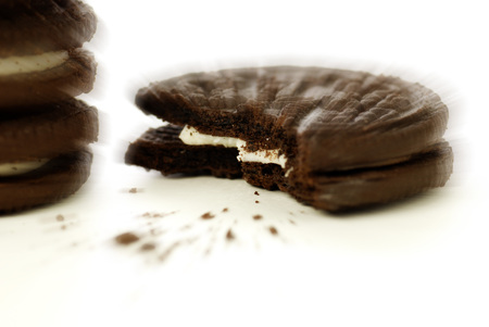 Chocolate cookies with creme filling and crumbs on white background