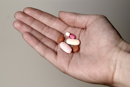 Detail of hand holding several pills for medical or healthの写真素材