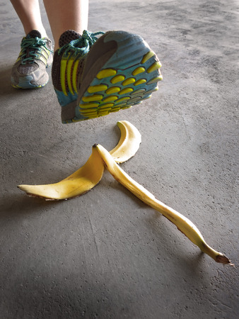 Person stepping on banana peel and slipping accident sidewalk floorの写真素材